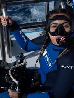 Margaux Le Brun en combinaison UNESCO, masque relevé, sur le bateau