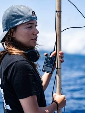 Ingénieure du son au casque tenant la perche à bord