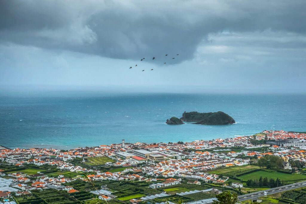 A stunning aerial view over Vila Franca do Campo and the Atlantic Ocean with dramatic clouds.