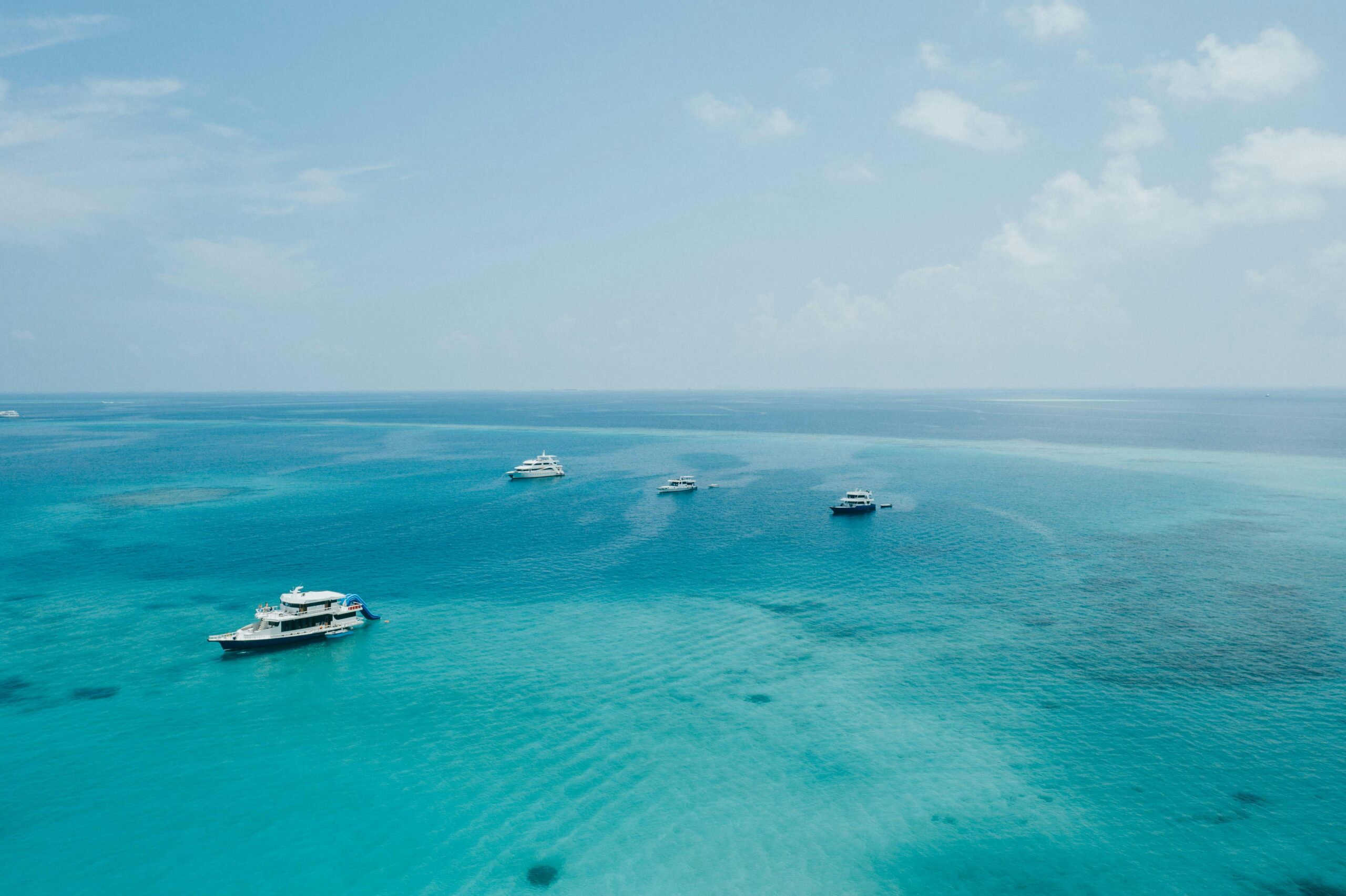 Picturesque view of contemporary yachts and motorboats floating on transparent turquoise seawater beneath blue sky on sunny day