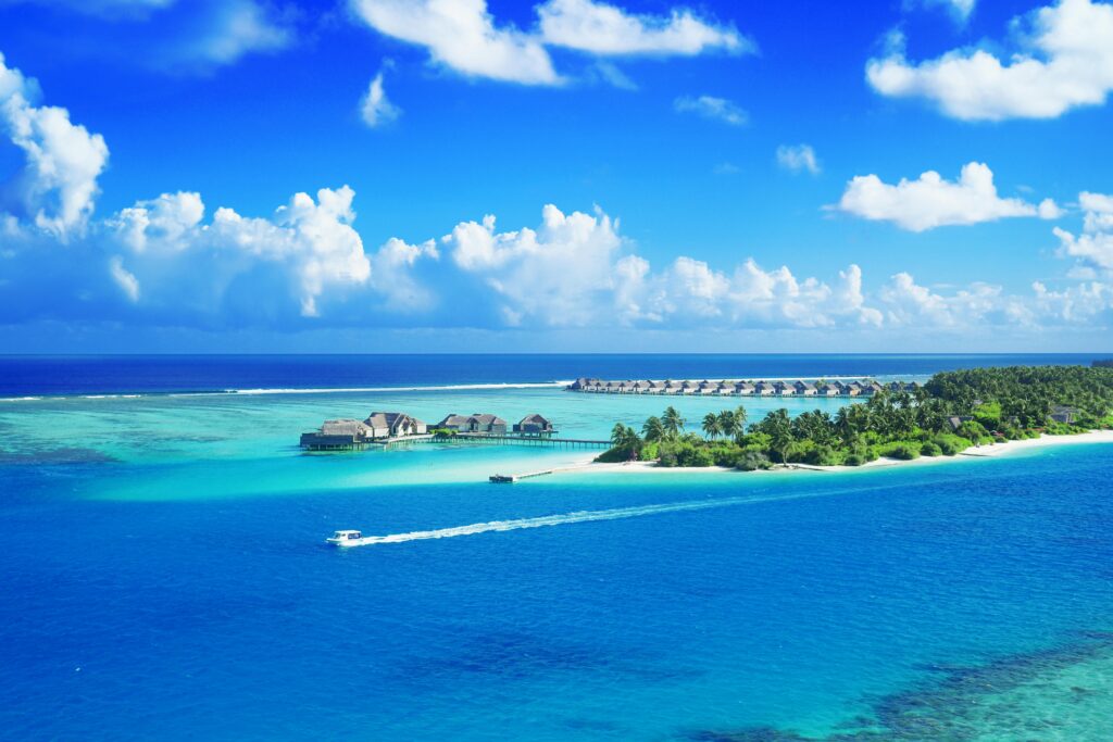 Crystal clear waters surround a luxurious Maldives resort under a bright blue sky.